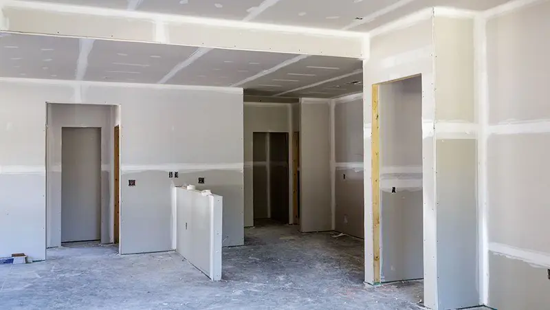 Drywall finisher skim coating a wall to a smooth Level 5 finish