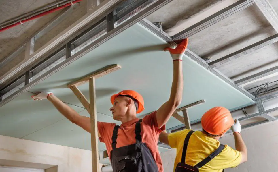 Installer screwing a drywall sheet to wall studs in a Tampa home