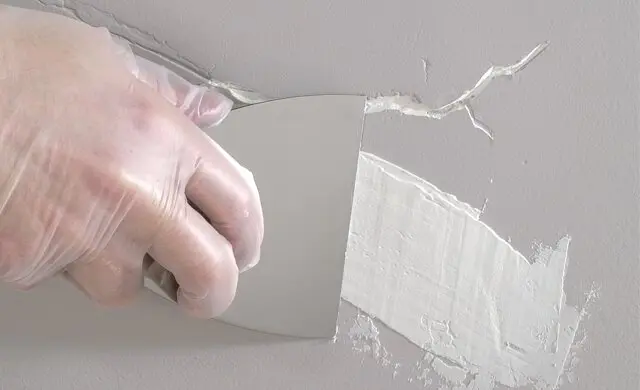 Hairline crack running from the corner of a door frame in a painted drywall wall