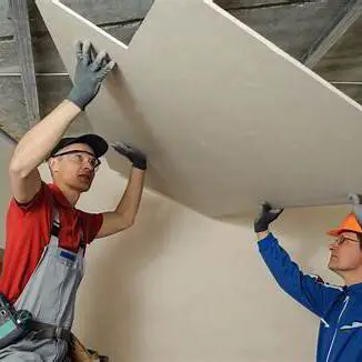Homeowner comparing two written drywall repair quotes at a kitchen table