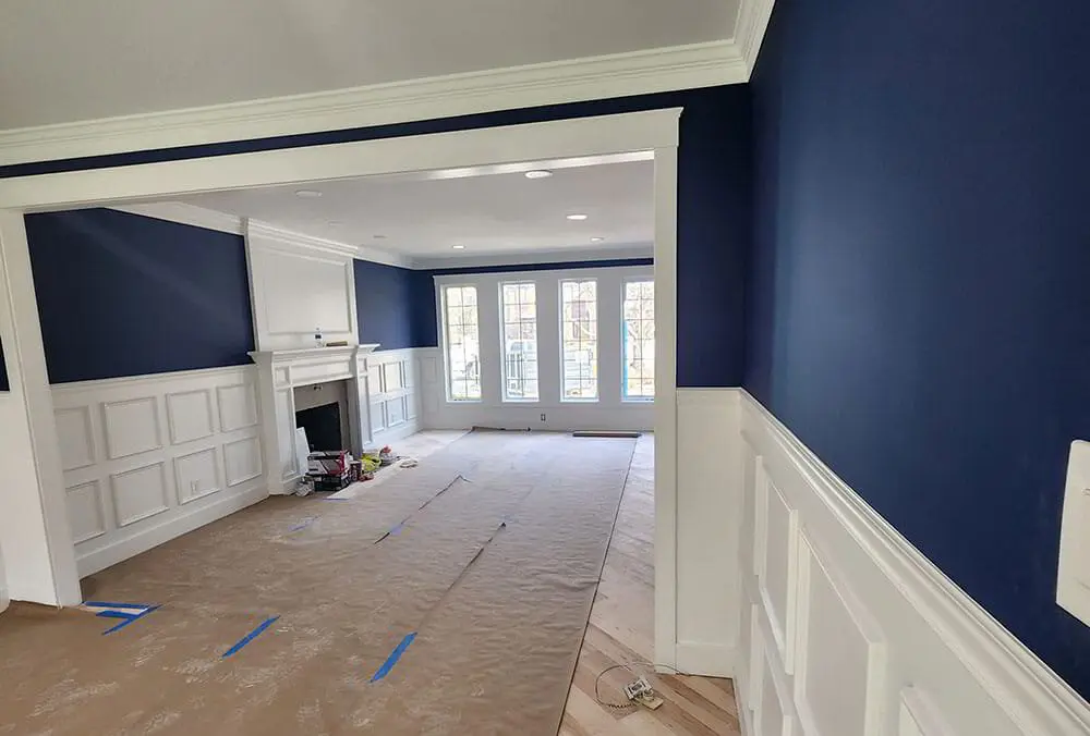 Painter sanding a primed drywall patch before applying interior paint