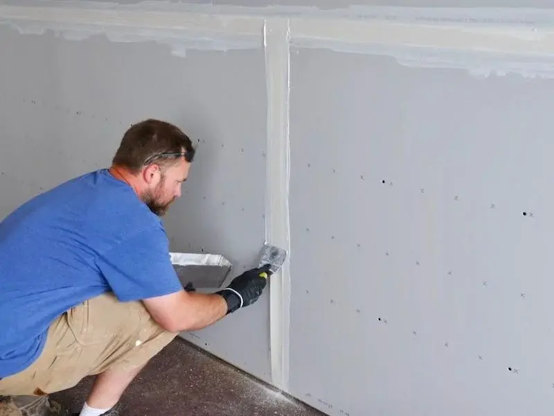 Drywall finisher applying a skim coat for a Level 5 smooth wall finish