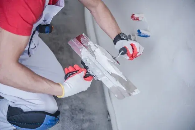 Drywall tape being embedded in joint compound over a wall crack