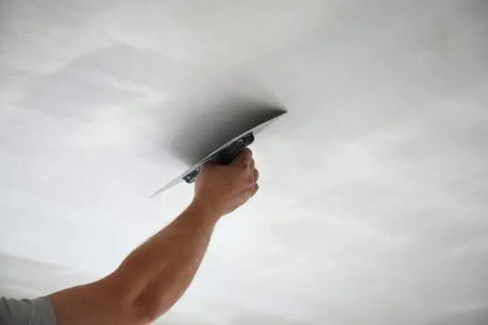 Technician taping a drywall seam in a residential living room