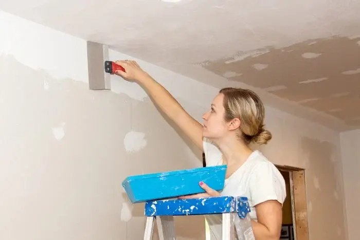Homeowner applying joint compound to a small drywall patch